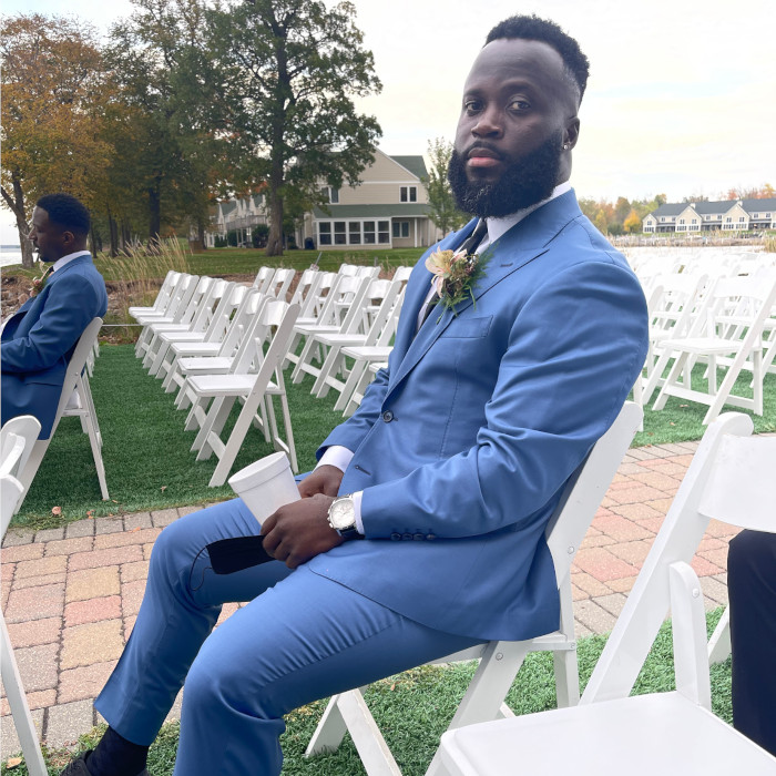 a man sitting in white char wearing a hartter manly suit