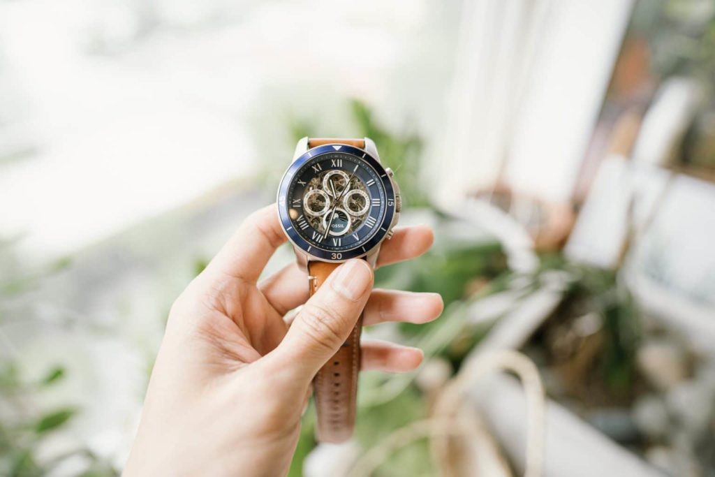 A hand holding a luxury watch with leather strap