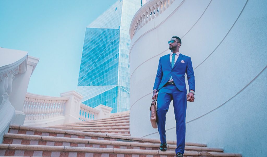 Man in blue suit standing on stairs. The suit has the right fit through the trousers