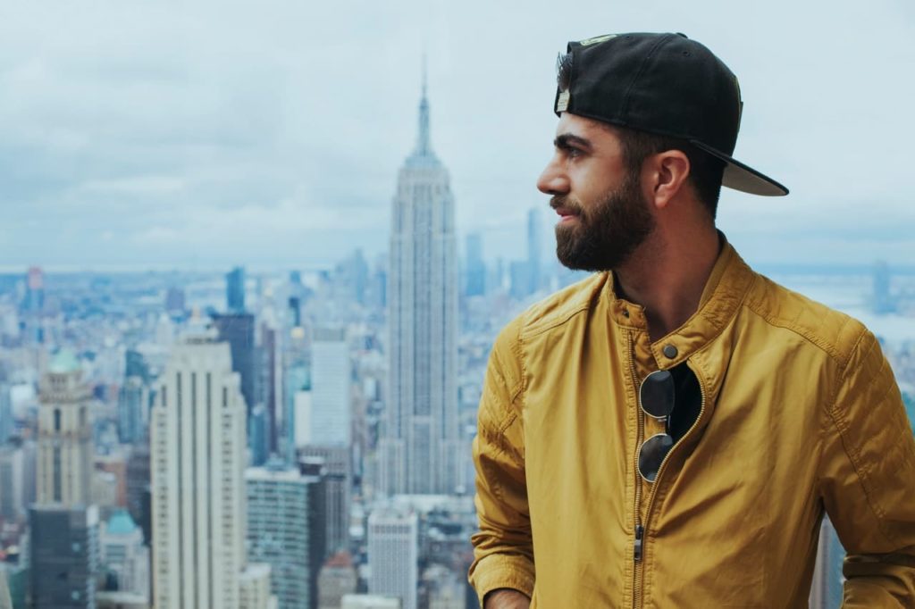 Man with hat and yellow zip up with clean facial hair and groomed neckline